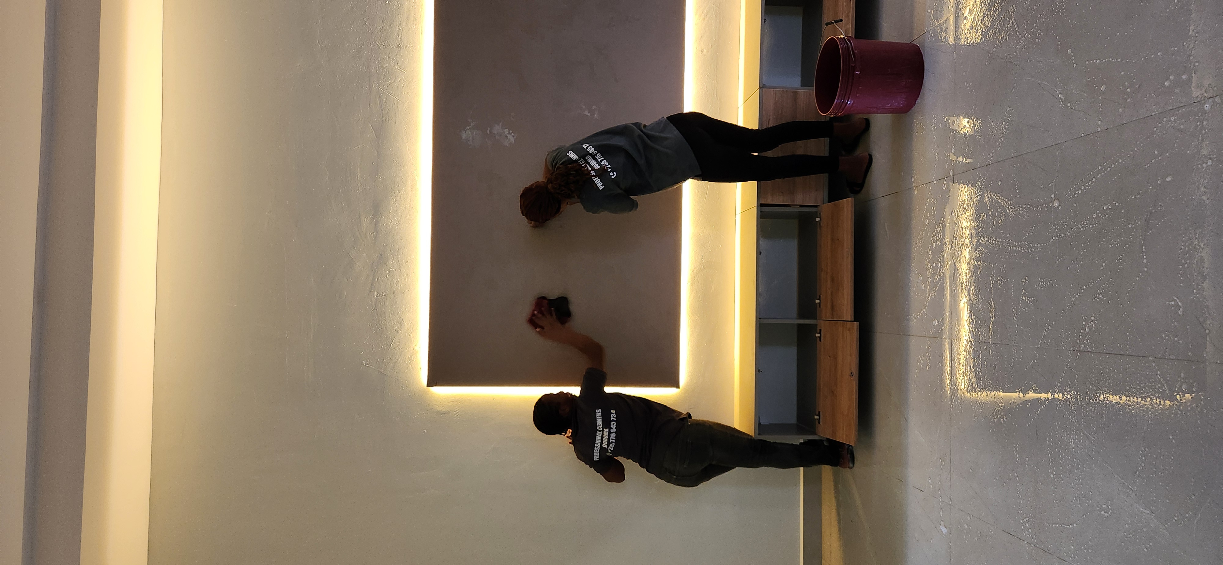 A team cleaning a backlit feature mirror and vanity.