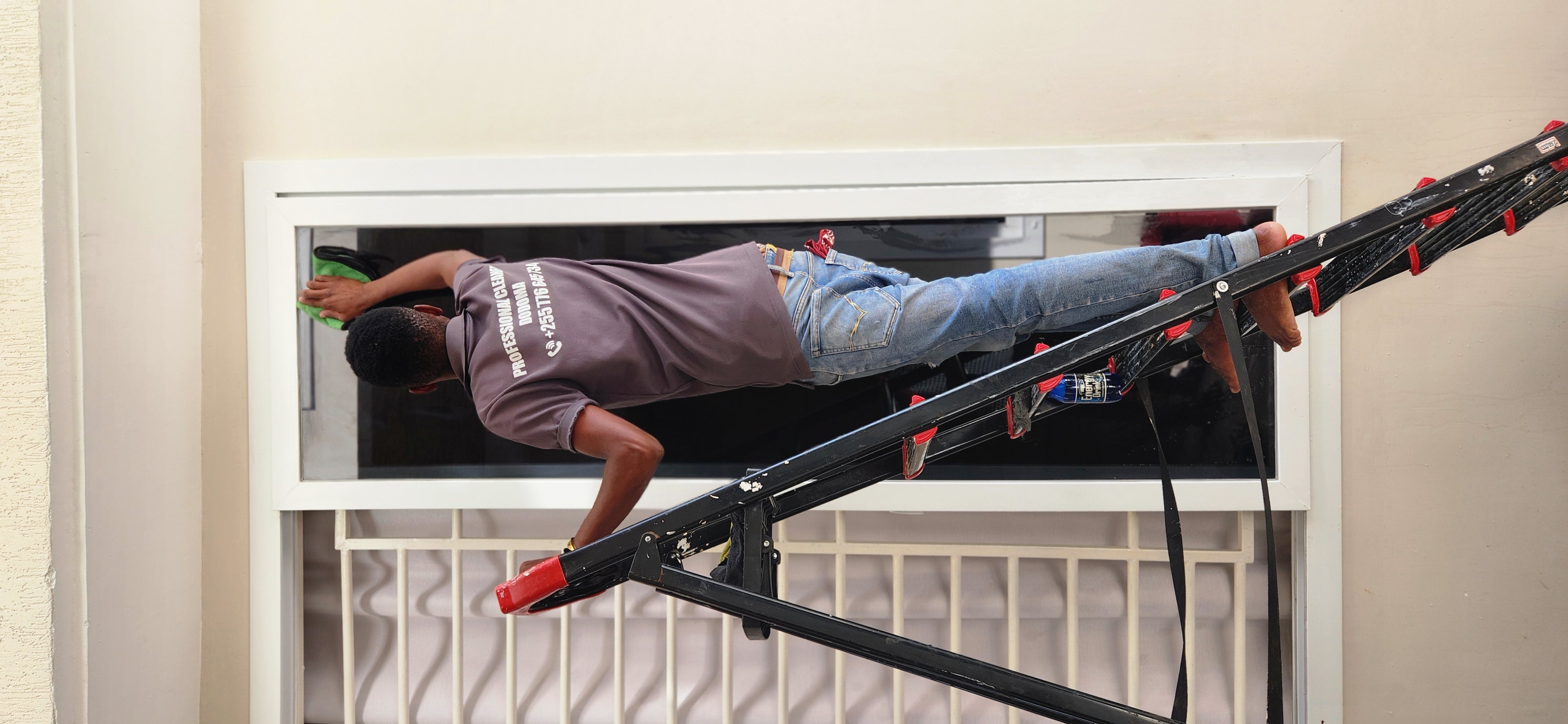 A cleaner on a ladder cleaning a high interior window after construction.